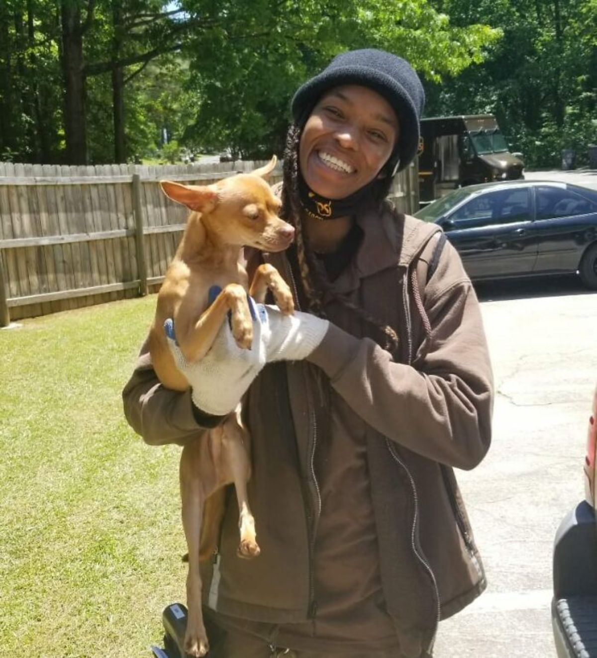 female ups driver holding a brown dog in her arms
