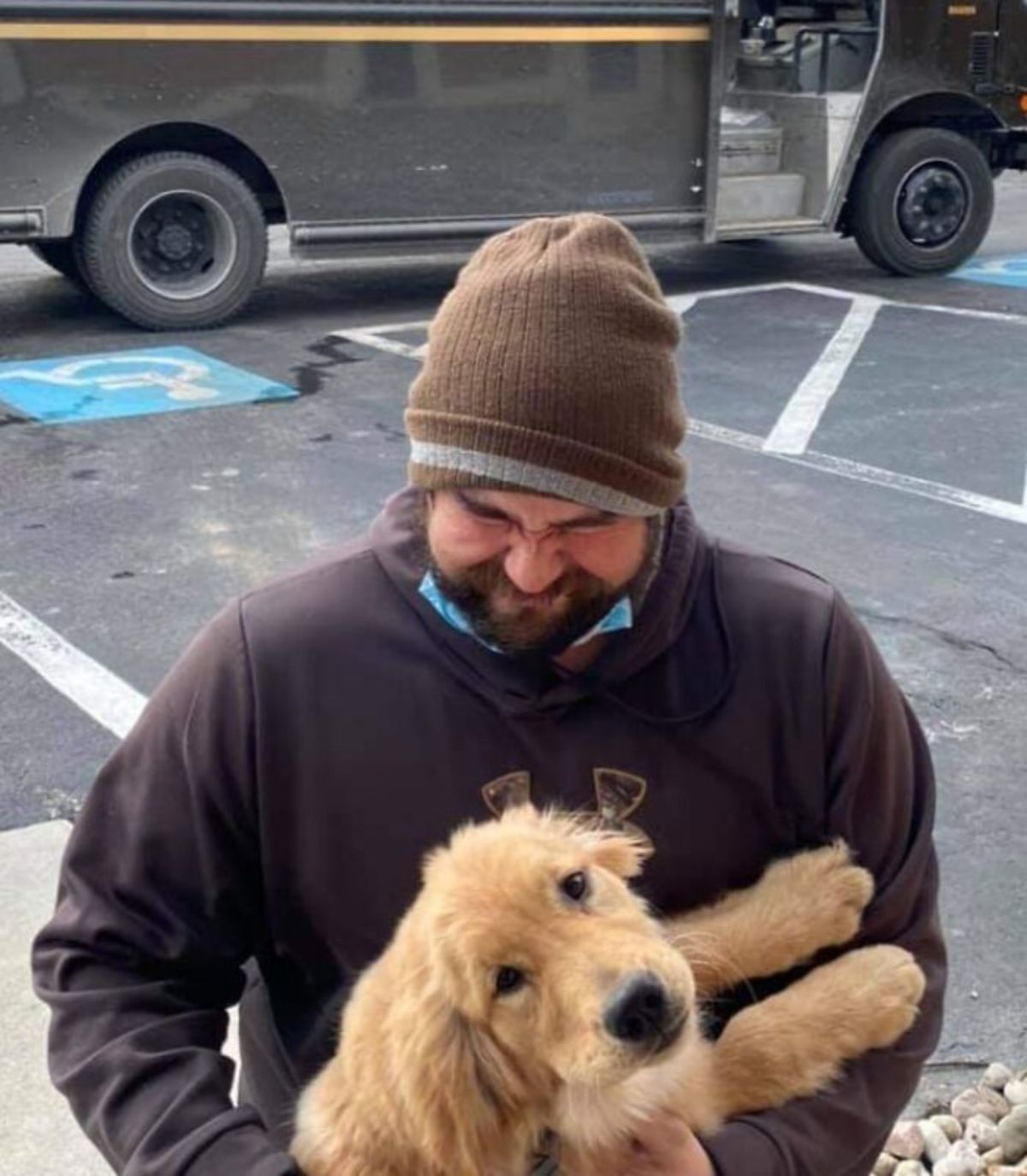 male ups driver with a golden retriever puppy on the lap