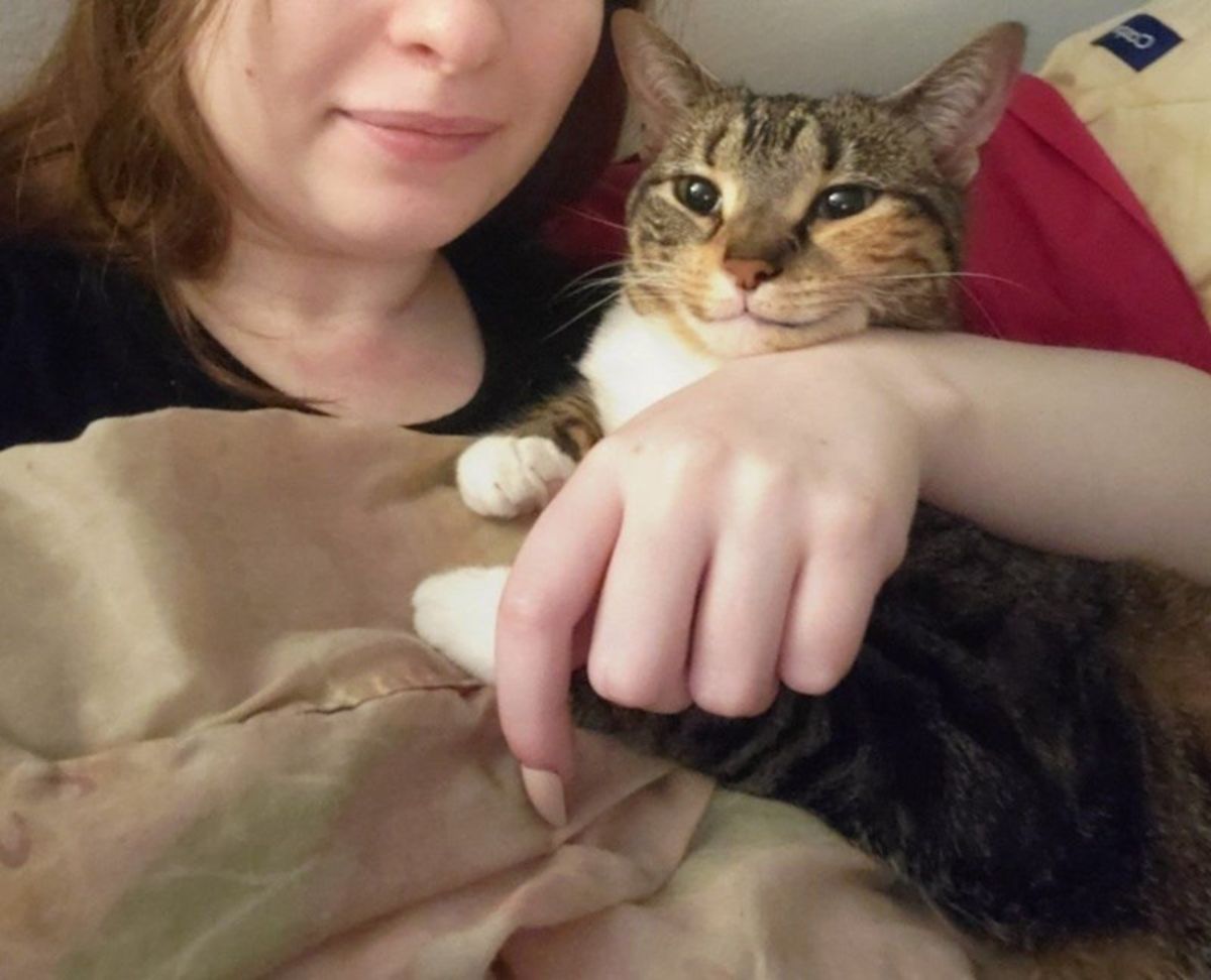 a smiling cat being held by a woman