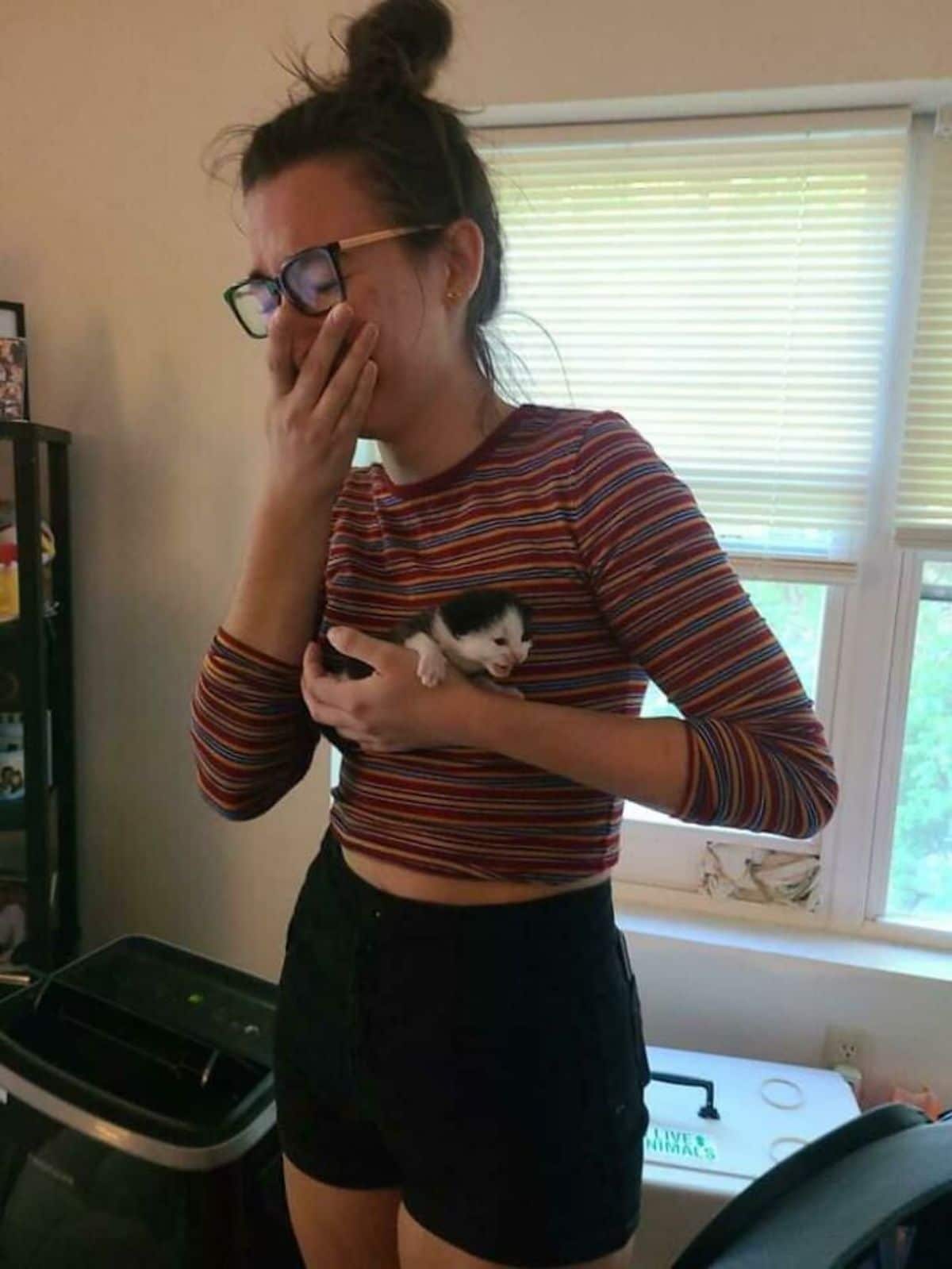 a woman crying and holding a screaming black and white kitten