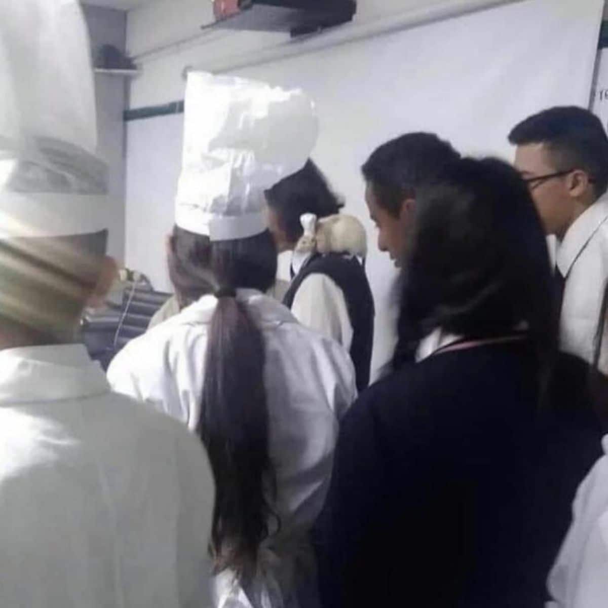 light brown rate with a small white chef's hat sitting on the shoulder of a chef in the middle of a group of chefs