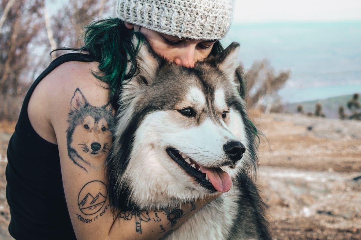 Woman with tattoes holding fluffy Eskimo dog 