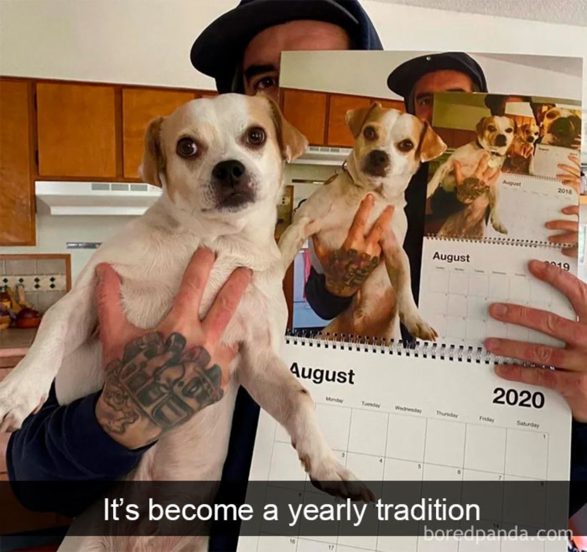 man holding up brown and white dog next to a calendar that has an image of this with a caption saying it's become a yearly tradition