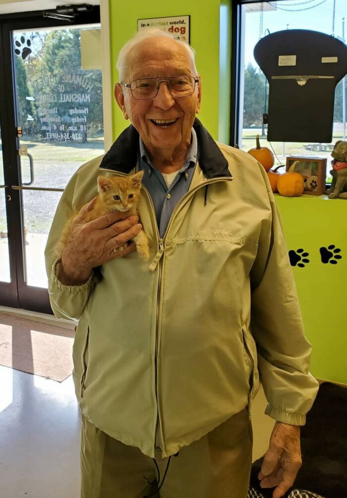 small orange kitten being held by an old man