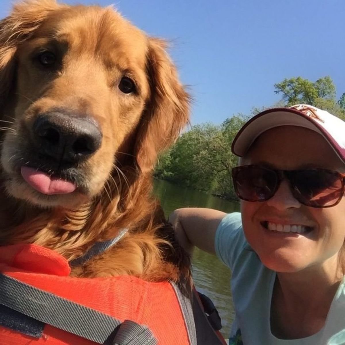 woman posing with golden retriever who has its tongue sticking out slightly
