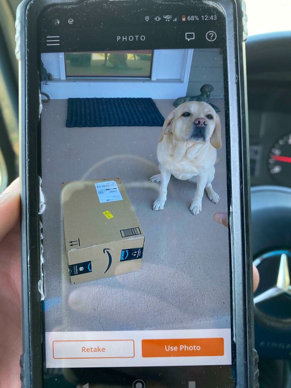 a delivery confirmation photo on a phone of a yellow labrador retriever sitting at a door with an amazon package