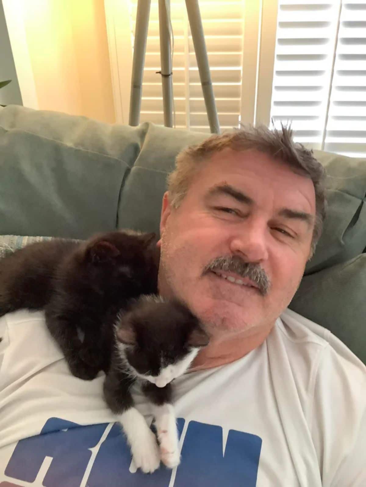 black and white kitten on an old man's shoulder