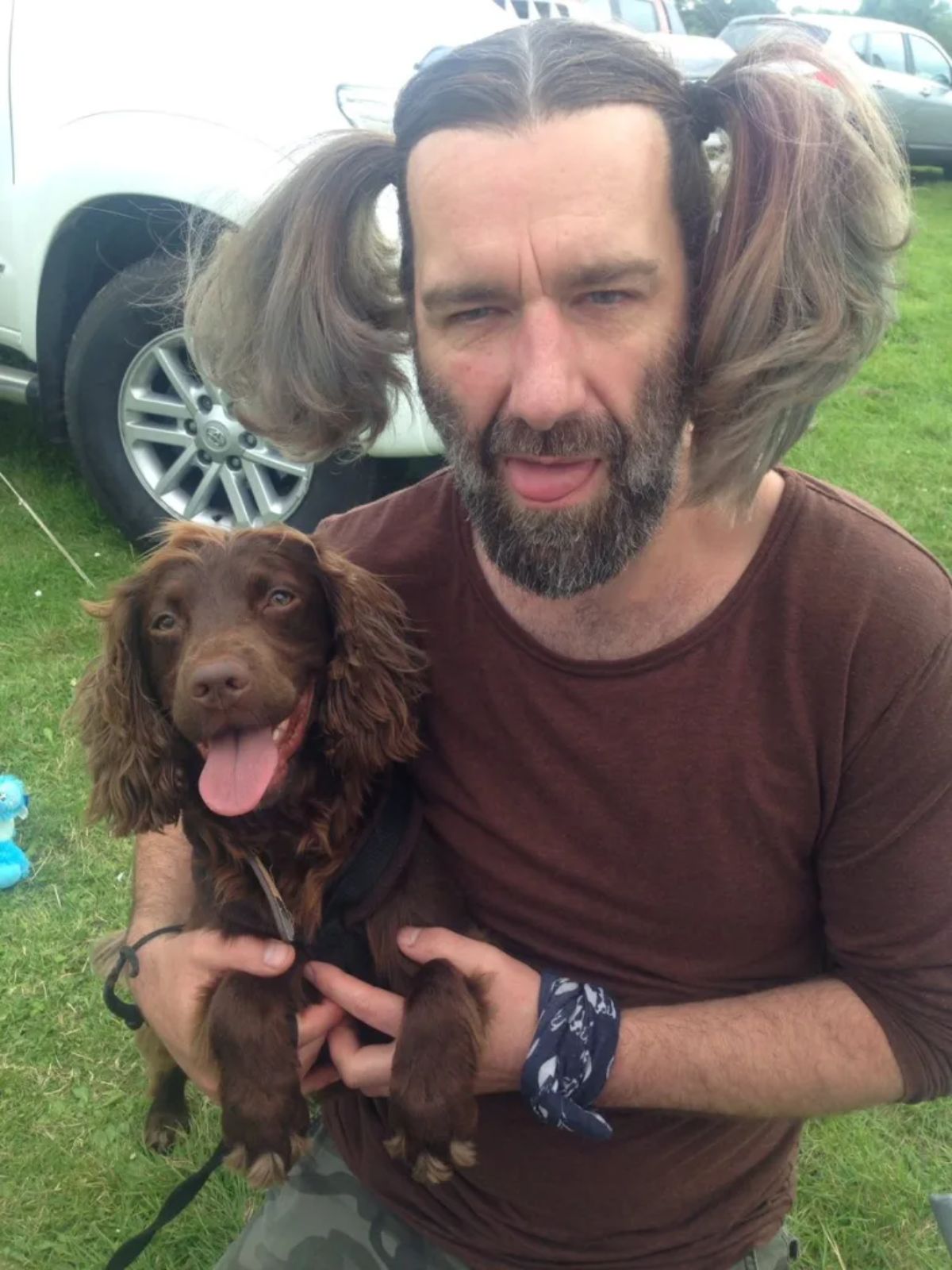 brown puppy with curly fluffy ears held by a man with brown pig tails