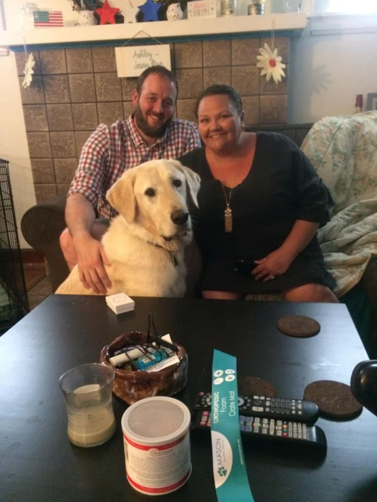 husband and wife couple posing with a large retriever
