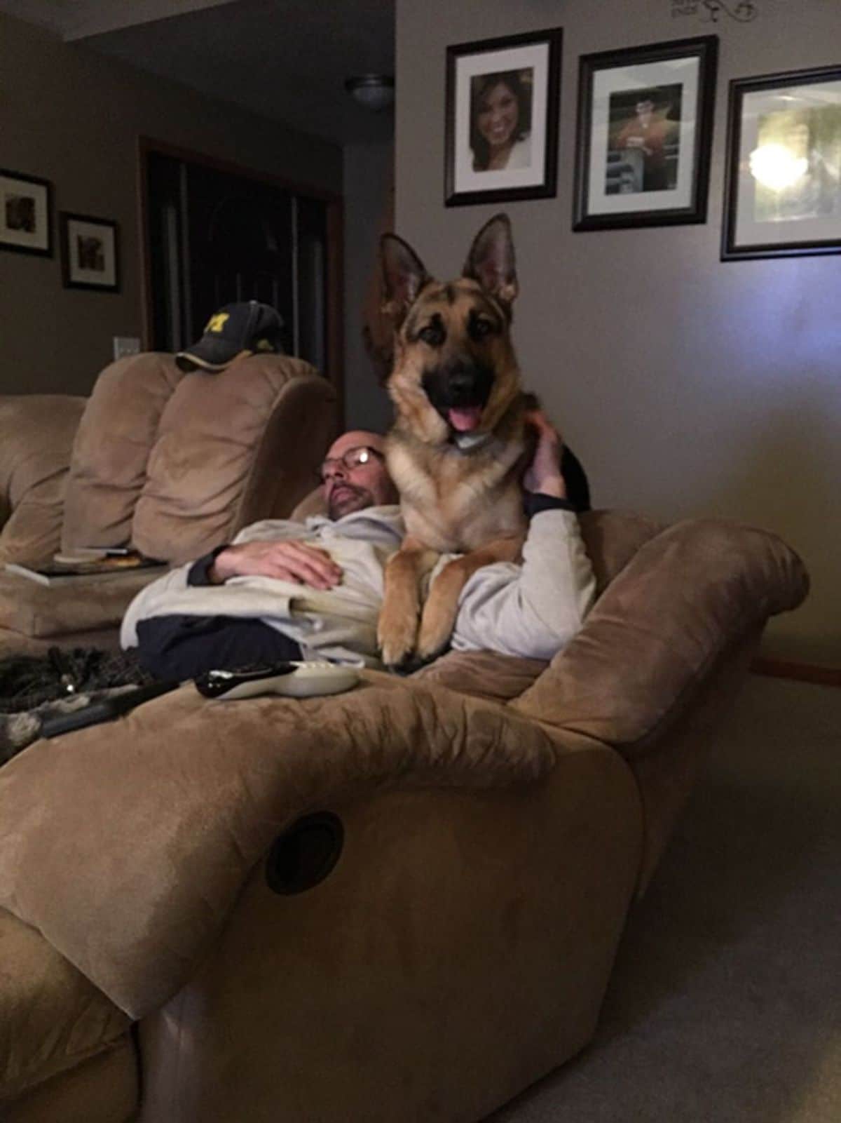 man laying on a brown couch with a german shepherd laying on him