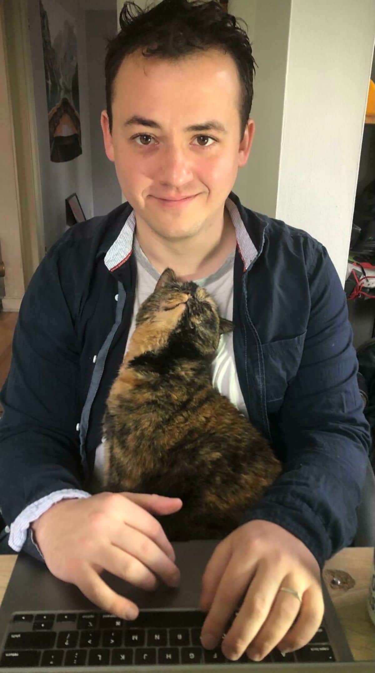 orange and black cat in a man's arms looking up lovingly at him