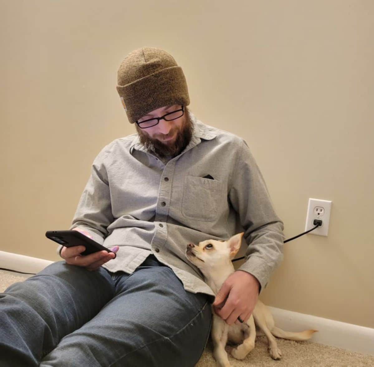 white chihuahua sitting on the floor next to a man and they are looking at each other lovingly