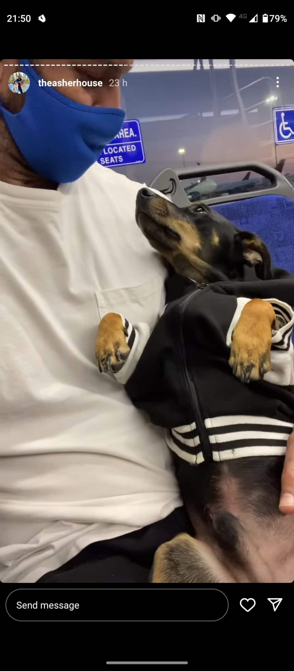 black and brown dog in a black and white jacket being cuddled by a man and the dog is looking up at him lovingly