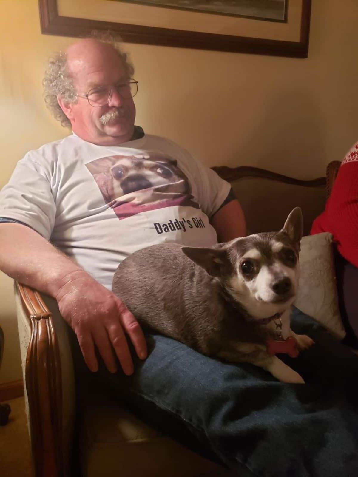 small brown and white dog sitting on an old man's lap with the dog's face printed on the man's shirt and under the photo in the shirt it says Daddy's Girl