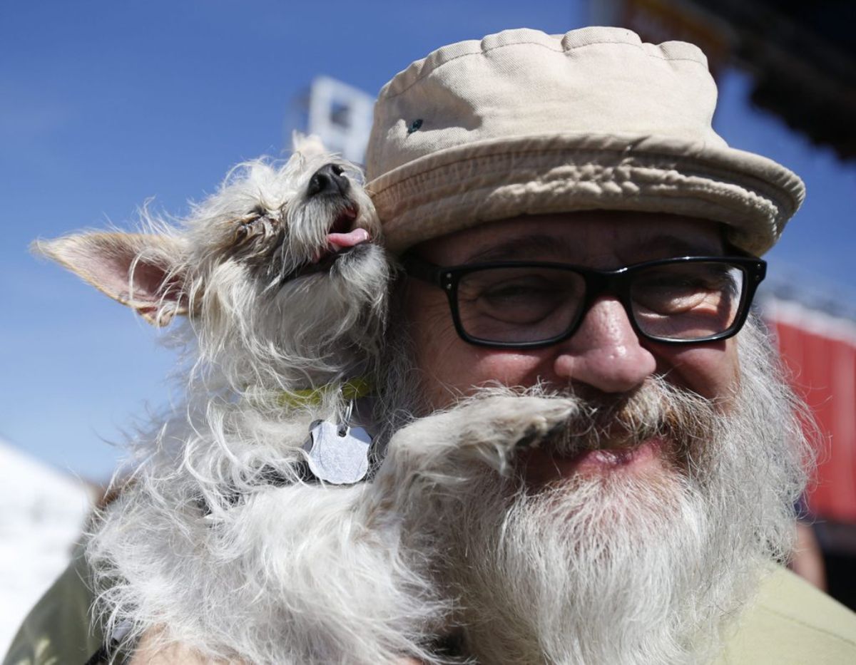 small fluffy white dog being held on the shoulder by an old man