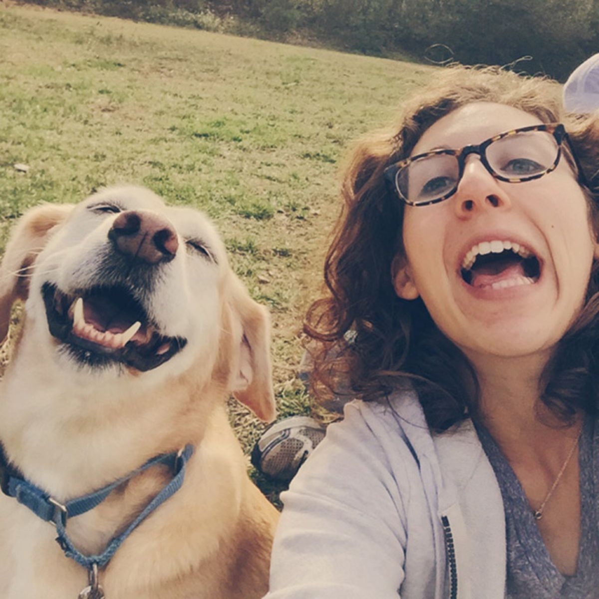 smiling white and brown dog next to a smiling woman