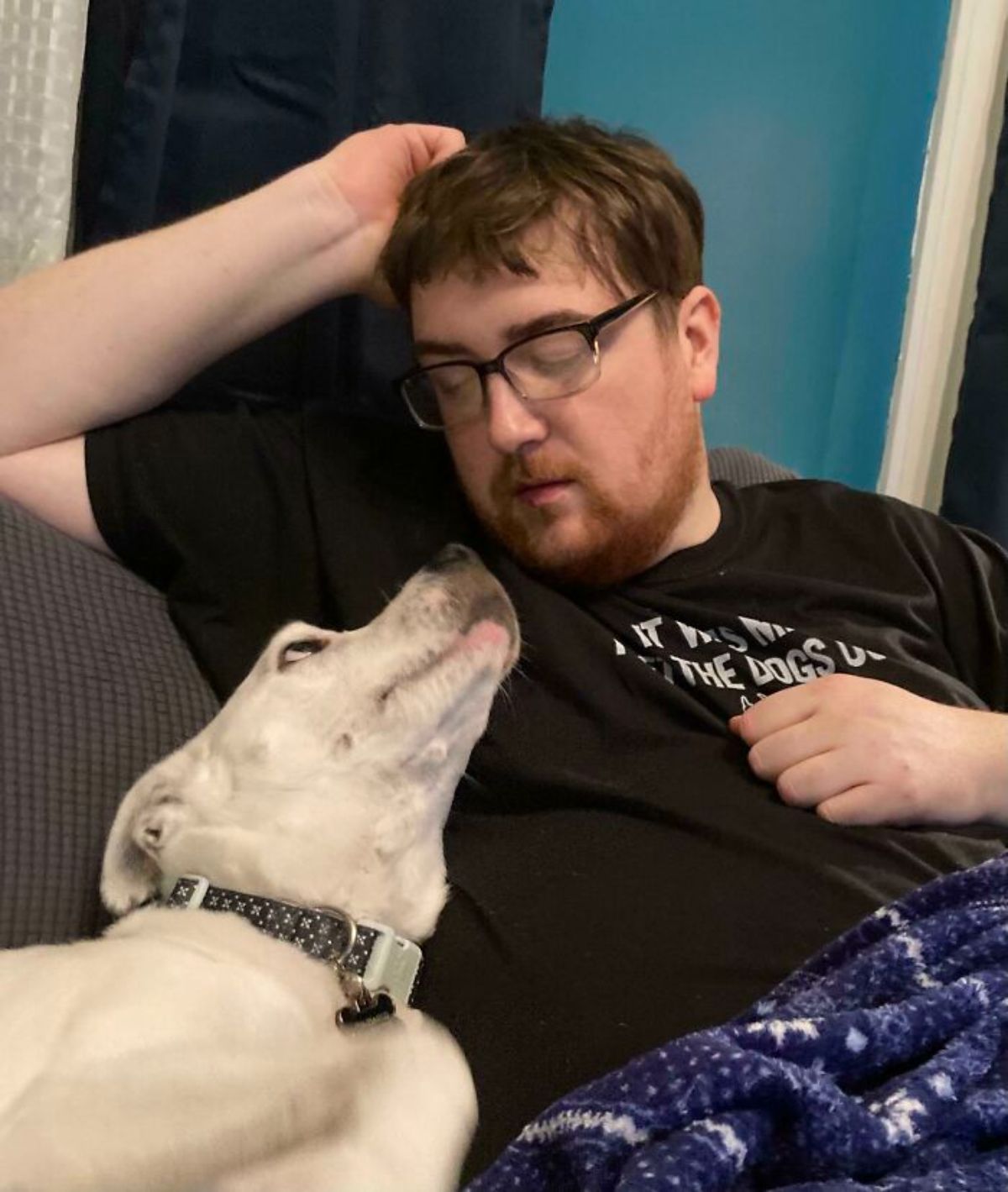 white dog laying next to a man and looking up lovingly at the man
