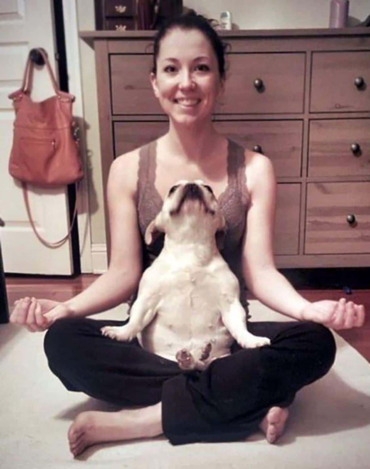 woman sitting cross-legged with a whit pug on her lap