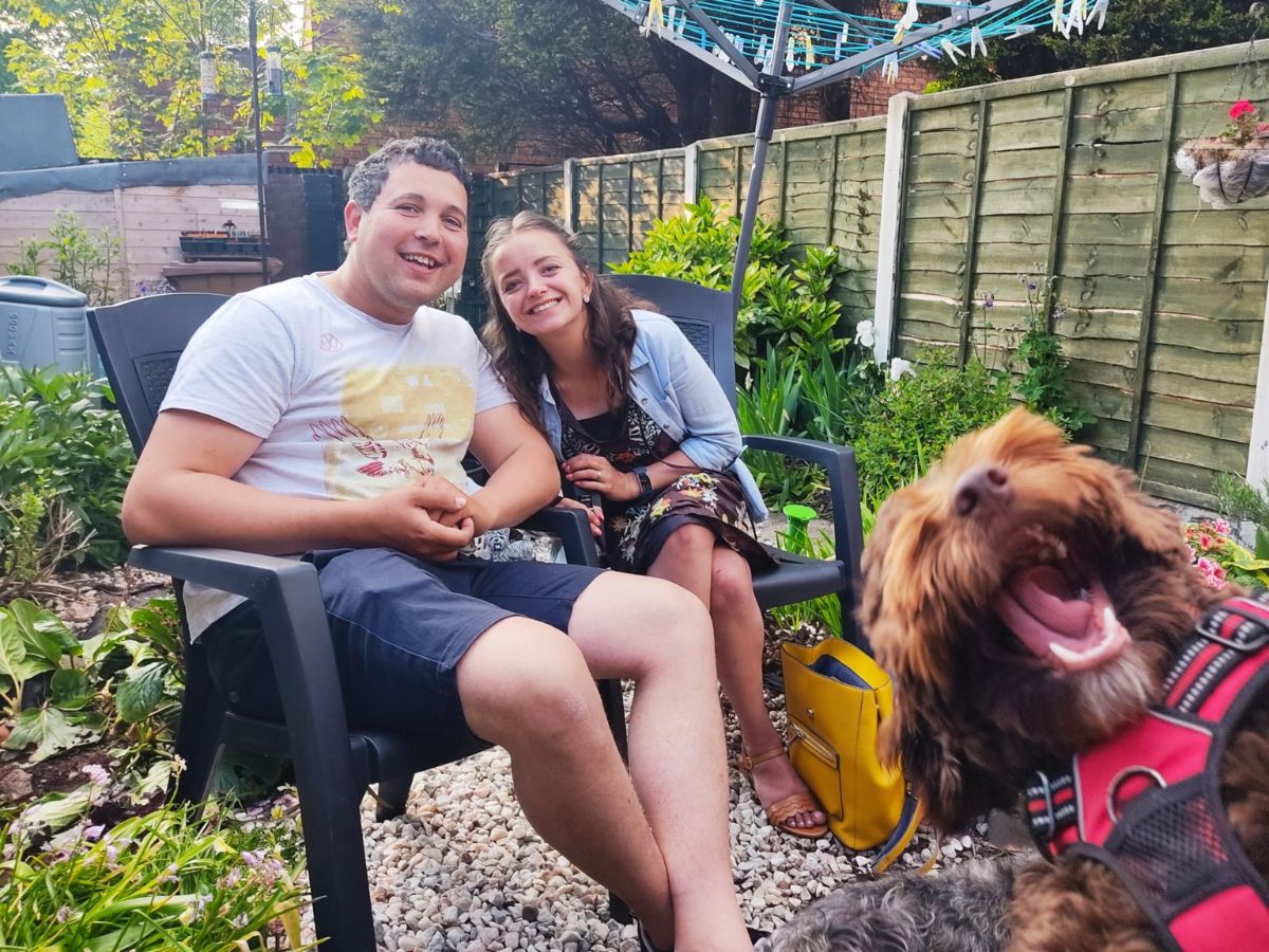 smiling fluffy brown dog in the corner of a couple's photo